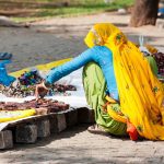 Indian woman in colorful sari sells souvenirs, bangles and cheap jewelry at street market place. Fort Cochin (Kochin), Kerala, India